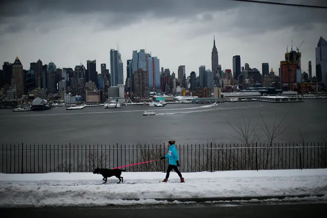 A woman walks her dog in Weehawken, New Jersey, as the Empire State Building and Middle Manhattan are seen after a snowstorm in New York, U.S., March 14, 2017. (Photo by Eduardo Munoz/Reuters)