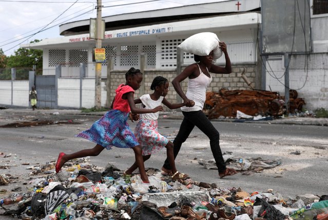A woman with two children carries their belongings as residents of the Lower Delmas flee their homes due to gang violence, in Port-au-Prince, Haiti on May 2, 2024. (Photo by Ralph Tedy Erol/Reuters)
