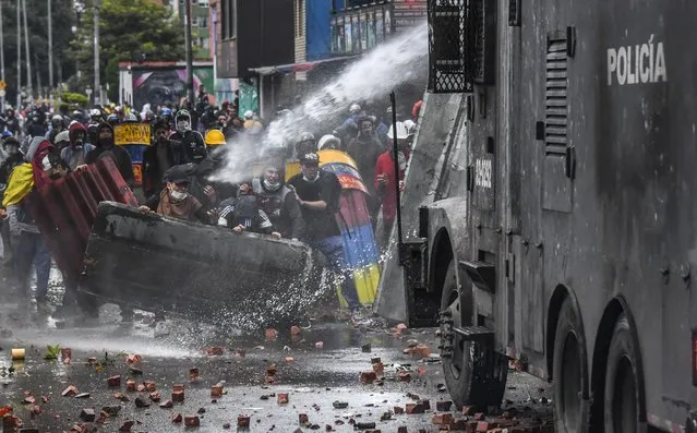 Police officers spray a water cannon at demonstrators during a protest against the government of Colombian President Ivan Duque in Bogota on June 9, 2021. (Photo by Juan Barreto/AFP Photo)