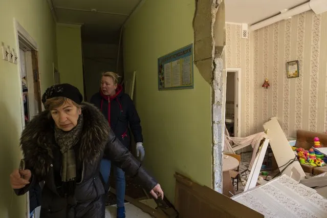 Women walk inside a school damaged among other residential buildings following a bombing in Kyiv, Ukraine, Friday, March 18, 2022. (Photo by Rodrigo Abd/AP Photo)