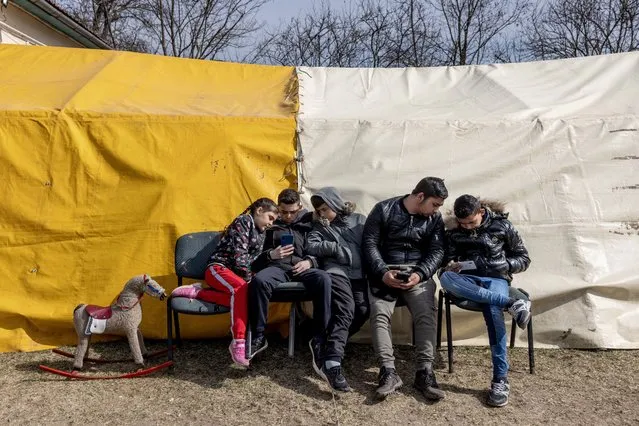 A refugee family sit in front of a tent at a temporary shelter offered by the “Free Christian Church” on March 20, 2022 in Uszka, Hungary. Prior to the war, Ukraine had an estimated population of 400,000 Roma, with the largest concentration in the region of Transcarpathia (or Subcarpathia), near Hungary's northwest border, where Hungarian is commonly spoken. (Photo by Janos Kummer/Getty Images)
