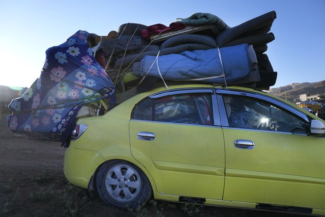 A Syrian refugee woman sits inside a car, as she prepares to go back home to Syria as a part of a voluntary return, in the eastern Lebanese border town of Arsal, Tuesday, May 14, 2024. Hundreds of Syrians refugees left a remote northeastern Lebanese town back to Syria in a convoy, amid a surge in anti-refugee sentiment in the small, crisis-hit country. Lebanese officials for years has urged the international community to resettle the refugees in other countries or help them return to Syria. (Photo by Hussein Malla/AP Photo)