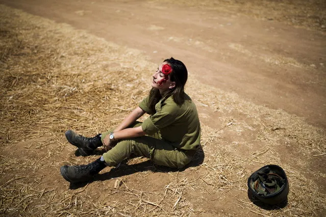 An Israeli soldier is partly covered in fake blood as she plays the role of a victim during a drill simulating a bomb attack on a train in Kiryat Gat, Israel June 4, 2015. (Photo by Amir Cohen/Reuters)