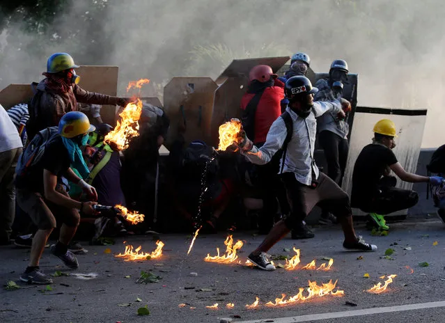 An opposition supporter throws a petrol bomb while clashing with riot security forces during a rally against President Nicolas Maduro in Caracas, Venezuela, May 18, 2017. (Photo by Marco Bello/Reuters)