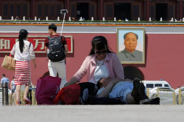 A couple takes a rest on the ground of Tiananmen Square where the portrait of late Chinese chairman Mao Zedong is seen, on the 50th anniversary of the start of the Cultural Revolution in Beijing, China, May 16, 2016. (Photo by Kim Kyung-Hoon/Reuters)