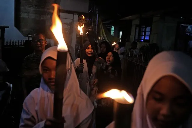 Young girls hold torches during a parade on the eve of Eid al-Fitr, the holiday marking the end of the holy fasting month of Ramadan, in Jakarta, Indonesia, Sunday, May 1, 2022. (Photo by Dita Alangkara/AP Photo)