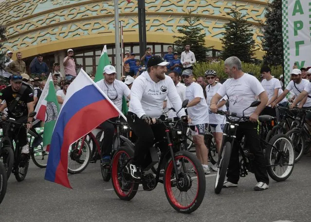 Chechen regional leader Ramzan Kadyrov, foreground, rides a bicycle decorated with a Russian national flag as he takes a part in a bicycle race in Chechnya's provincial capital Grozny, Russia, Sunday, Aug. 2, 2015. (AP Photo/Musa Sadulayev)