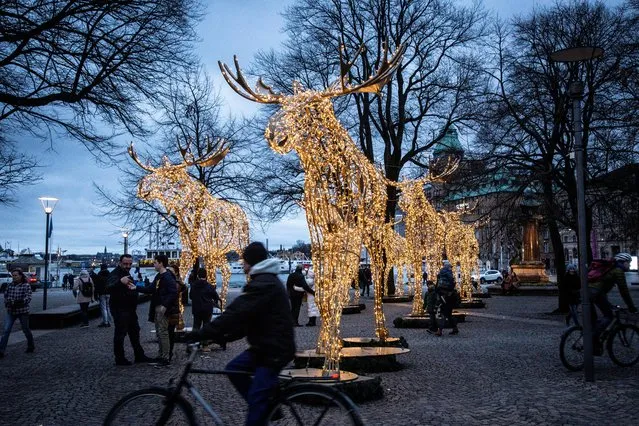 People stroll among Christmas light installations formed as elks at the Raoul Wallenberg Square in central Stockholm, Sweden on December 22, 2019. (Photo by Helena Landstedt/TT News Agency via Reuters)
