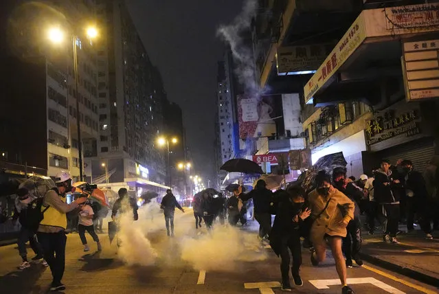 Protesters react as police fire tear gas during a demonstration in Hong Kong, early Wednesday, January 1, 2020. Chinese President Xi Jinping in a New Year's address Tuesday has called for Hong Kong to return to stability following months of pro-democracy protests that began in June over a proposed extradition law, and have spread to include other grievances and demands for more democracy. (Photo by Vincent Yu/AP Photo)