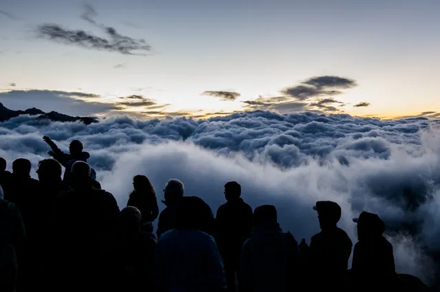 Tourists watch the sunrise above a sea of fog on Eggishorn moutain (2927 meters over sea level), in Fiesch, Switzerland, early Tuesday, July 28, 2015. (Photo by Dominic Steinmann/Keystone via AP Photo)