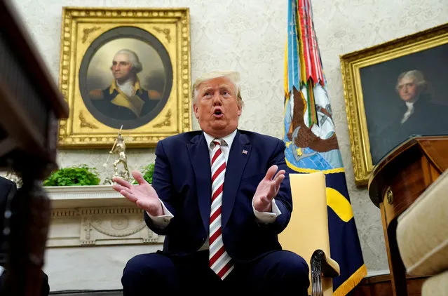 U.S. President Donald Trump answers questions while sitting in front of paintings of former U.S. presidents George Washington and Thomas Jefferson during his meeting with Romania's President Klaus Iohannis in the Oval Office of the White House in Washington, U.S. August 20, 2019. (Photo by Kevin Lamarque/Reuters)