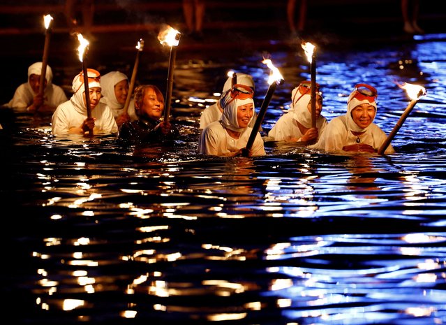 “Ama” female free divers, who harvest sea life from the ocean, lead volunteers as they swim with torches during Shirahama Ama matsuri in Minamiboso, Chiba Prefecture, Japan on July 20, 2024. (Photo by Kim Kyung-Hoon/Reuters)