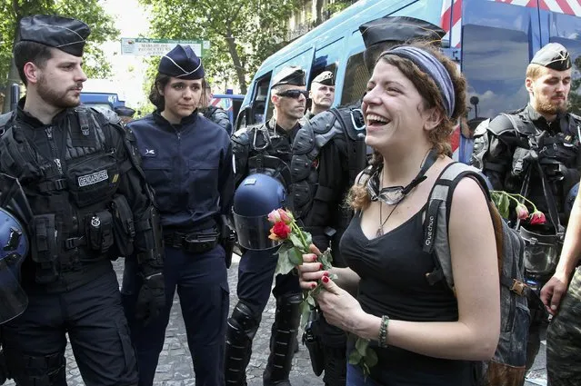 A woman reacts as she holds roses in front of French gendarmes and police during a demonstration against plans to reform French labour laws near the Place de la Bastille square in Paris, France, June 23, 2016. (Photo by Jacky Naegelen/Reuters)