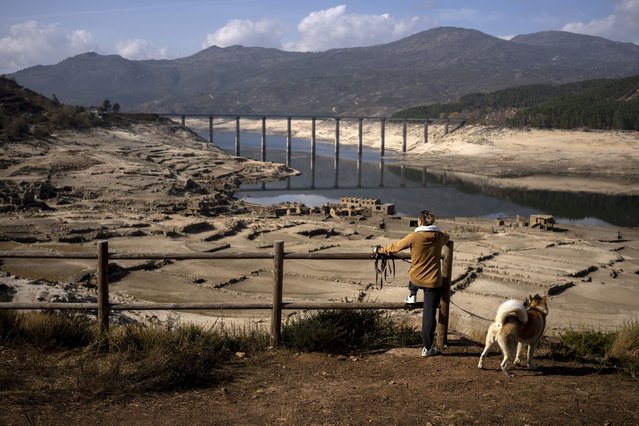 A man photographs the old village of Aceredo, submerged three decades ago when a hydropower dam flooded the valley and emerged now due to drought at the Lindoso reservoir, in northwestern Spain, Saturday, February 12, 2022. With rainfall levels this winter at one-third of the average in recent years, large swaths of Spain are experiencing extreme or prolonged drought. The situation is similar in neighboring Portugal, where 45% of the country was enduring “severe” or “extreme” drought conditions by the end of January, according to authorities. (Photo by Emilio Morenatti/AP Photo)