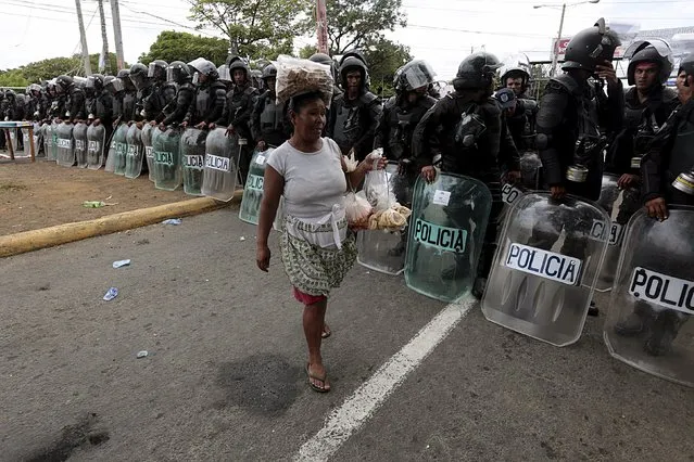 A street vendor sells candy and bread to riot police officers after a protest in front of the Supreme Electoral Council (CSE) building in Managua, Nicaragua August 12, 2015. The protesters said they were demonstrating to demand fairer elections in the country next year. (Photo by Oswaldo Rivas/Reuters)