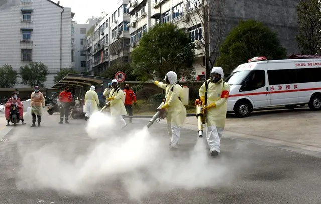 Volunteers in protective suits disinfect a residential compound, as the country is hit by the outbreak of a new coronavirus, in Taizhou, Zhejiang province, China, January 30, 2020. (Photo by Reuters/China Daily)