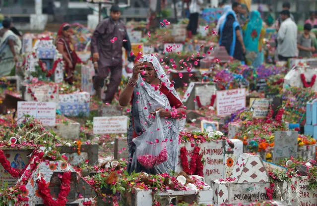 A woman of Devipujak tribe scatters rose petals on the grave of her deceased family members at a graveyard during Diwaso festival in which people decorate graves, pray and offer gifts to deceased relatives, in Ahmedabad, India, July 23, 2017. (Photo by Amit Dave/Reuters)