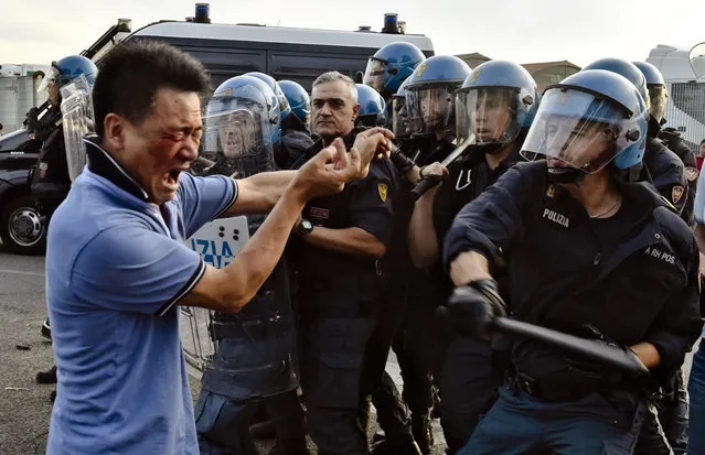 In this picture taken Thursday, June 30, 2016, italian Police officers in riot gears push back a protester during clashes with members of the local Chinese community in Sesto Fiorentino, on the outskirts of Florence Italy. Members of the Chinese community have clashed against police in a protest against what they say are excessive controls over their companies. Police lashed back with batons leaving several Chinese injured and bloodied on the ground. In interviews on Italian Television, Chinese protesters complained the Italian government continues to do raids on their businesses frequently fining them unfairly for infractions of Italian laws. (Photo by Maurizio Degli'Innocenti/ANSA via AP Photo)