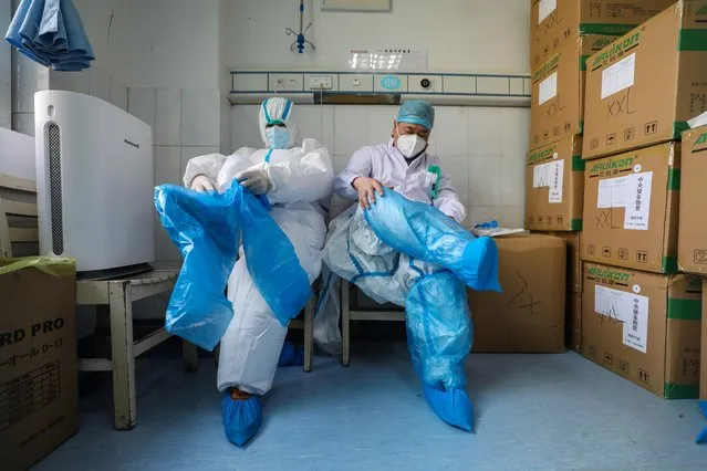 Medical workers put on protective suits at a preparation room next to isolation wards at Wuhan Red Cross Hospital, February 24, 2020. (Photo by Reuters/China Daily)