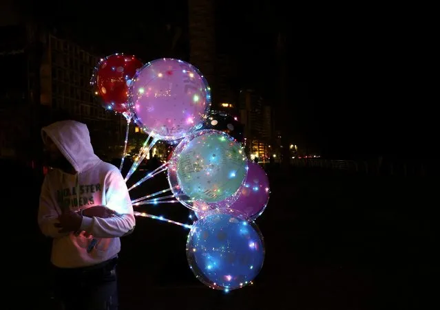 A street vendor sells light balloons at night during a power cut at Beirut's seaside corniche, Lebanon on April 27, 2022. (Photo by Mohamed Azakir/Reuters)