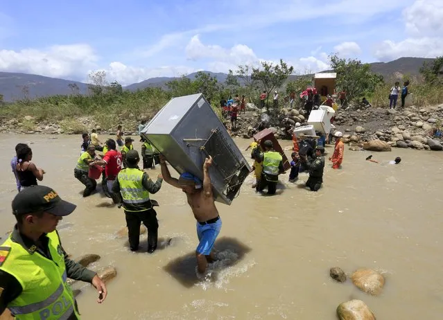 A man carries a refrigerator while crossing the Tachira river border with Venezuela into Colombia, near Villa del Rosario village August 25, 2015. The ongoing crisis on the border between Colombia and Venezuela should not be used for political point-scoring by leaders in either country ahead of elections in coming months, the Colombian government said on Tuesday. (Photo by Jose Miguel Gomez/Reuters)