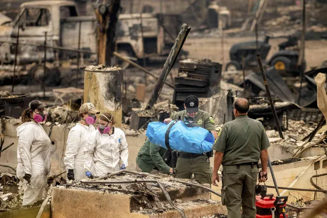 Sheriff's Deputy Johnson carries remains of a McKinney Fire victim from a destroyed home on Monday, August 1, 2022, in Klamath National Forest, Calif. (Photo by Noah Berger/AP Photo)