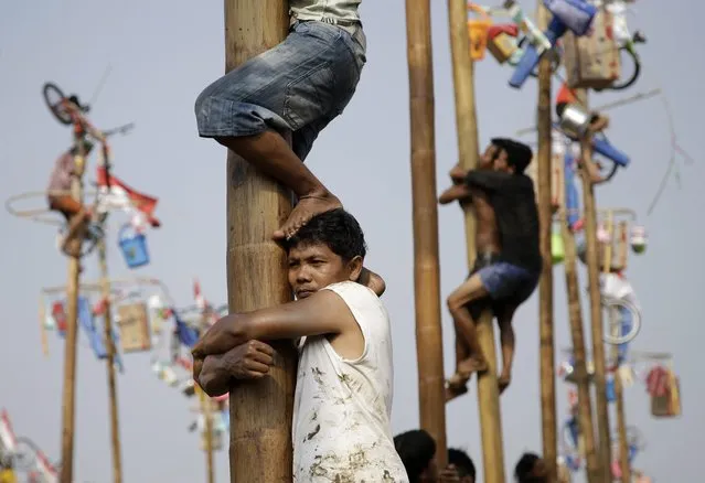 Participants struggle to reach the prizes during a greased-pole climbing competition held as a part of the independence day celebrations in Jakarta, Indonesia, Sunday, August 17, 2014. (Photo by Dita Alangkara/AP Photo)