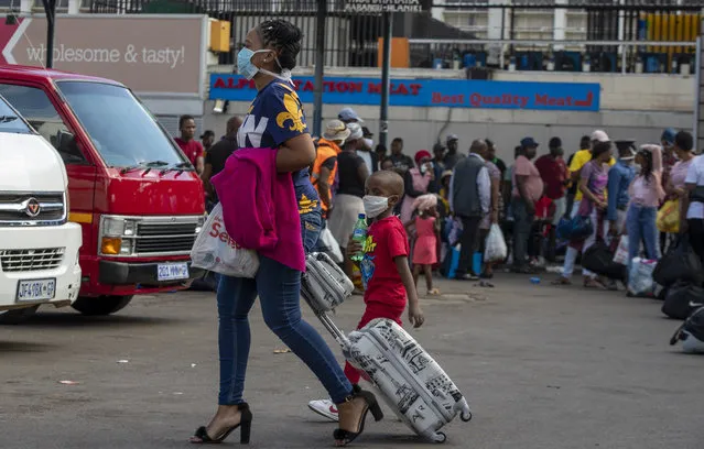 A woman with her child wearing face masks to protect against coronavirus, walk at a taxi rank in Johannesburg, South Africa, Thursday, March 26, 2020. People are preparing, with just hours before South Africa goes into a nationwide lockdown for 21-days in an effort to mitigate the spread to the coronavirus. (Photo by Themba HadebeAP Photo)