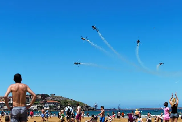 People watch as the Spanish Air Force aerobatic group Patrulla Aspa flies over San Lorenzo beach during an aerial exhibition in Gijon, northern Spain, northern Spain, July 24, 2016. (Photo by Eloy Alonso/Reuters)