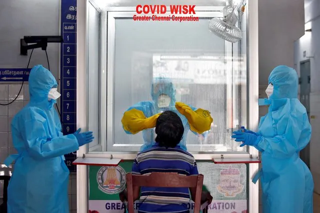 A doctor in a protective chamber takes a swab from a man to test for coronavirus disease (COVID-19) at a newly installed Walk-In Sample Kiosk (WISK) in a government-run hospital in Chennai, India, April 13, 2020. (Photo by P. Ravikumar/Reuters)