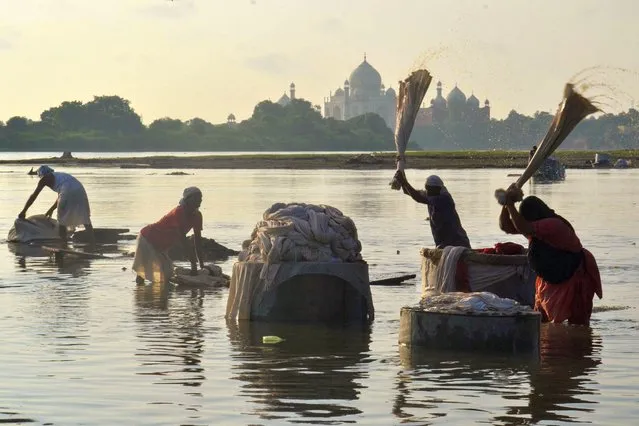 People wash clothes at Hathi Ghat along the Yamuna River with the Taj Mahal seen in the background in Agra on August 25, 2022. (Photo by Pawan Sharma/AFP Photo)