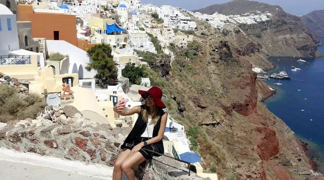 A tourist takes a selfie in the village of Oia on the Greek island of Santorini, Greece, July 1, 2015. (Photo by Cathal McNaughton/Reuters)