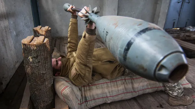 Ukrainian serviceman takes his exercises with 35 kg weight made from 120mm mortar, not far of front line in Vodyane village of Donetsk area, Ukraine, 16 October 2017. Two Ukrainian soldiers were wounded on a past day when pro-Russian rebels attacked Ukrainian army positions in Donbas, according to the local media report. (Photo by Sergey Vaganov/EPA/EFE)