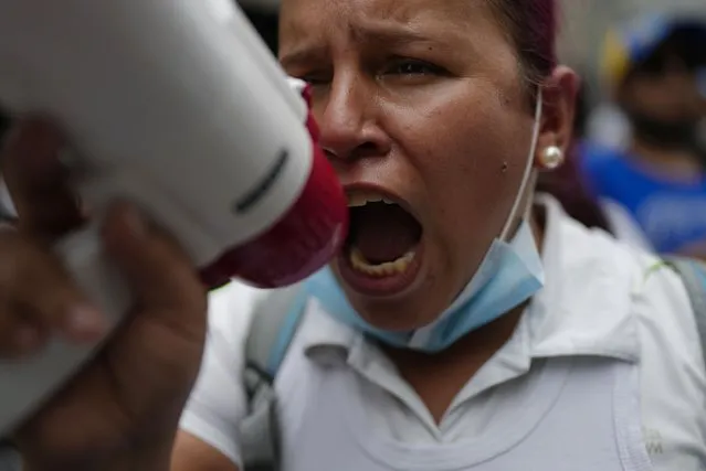 A nurse uses a megaphone during a protest by active and retired public workers demanding the government pay their full benefits and respect collective bargaining agreements, in Caracas, Venezuela, Tuesday, August 23, 2022. (Photo by Ariana Cubillos/AP Photo)