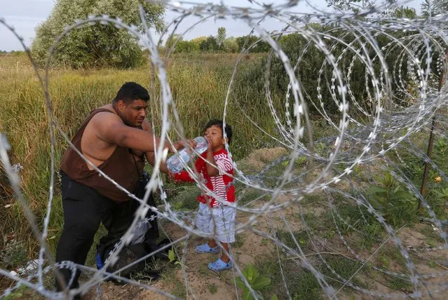 A migrant gives a child water as they wait on the Serbian side of the border with Hungary in Asotthalom, September 15, 2015. Hundreds of migrants spent the night in the open on Serbia's northern border with Hungary, their passage to western Europe stalled on Tuesday by a Hungarian crackdown to confront the continent's worst refugee crisis in two decades. (Photo by Laszlo Balogh/Reuters)