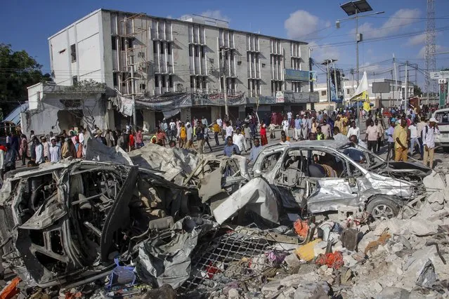 People walk amidst destruction at the scene, a day after a double car bomb attack at a busy junction in Mogadishu, Somalia Sunday, October 30, 2022. Somalia's president says multiple people were killed in Saturday's attacks and the toll could rise in the country's deadliest attack since a truck bombing at the same spot five years ago killed more than 500. (Photo by Farah Abdi Warsameh/AP Photo)