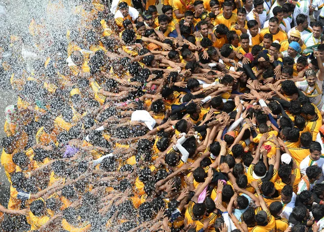 Indian Hindus devotees are showered with water while taking a pledge before forming a “human pyramid” during the dahi handi (curd pot) celebrations of Janmashtami, which mark the birth of Hindu god Lord Krishna, in Mumbai on August 25, 2016. India's top court on August 17, 2016, has banned children from taking part in a popular but potentially dangerous religious festival in the country's west that sees young boys scale human pyramids. The Supreme Court barred children aged under 18 from scaling the pyramids and restricted their height to 20 feet (six metres) following a string of accidents in recent years. (Photo by Indranil Mukherjee/AFP Photo)