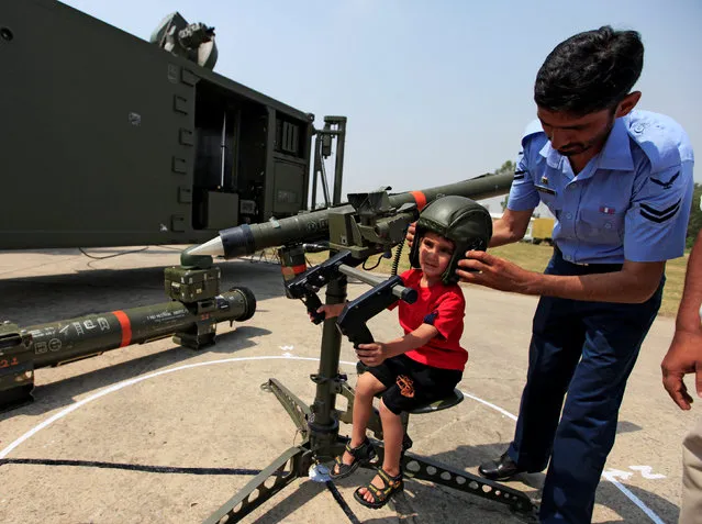 A member of the Pakistan air force helps a child to play with a weapon during a ceremony to commemorate Defence Day, or Pakistan's Memorial Day, at the Nur Khan airbase in Islamabad, Pakistan, September 6, 2016. (Photo by Faisal Mahmood/Reuters)