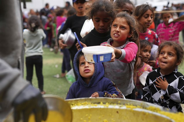 Palestinian children receive donated food at a distribution center in Nuseirat, central Gaza Strip, Friday, April 11, 2025. (Photo by Abdel Kareem Hana/AP Photo)
