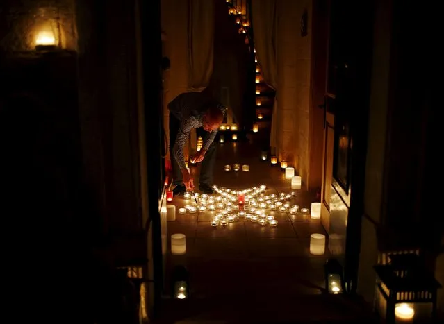 A resident lights candles laid down in the form of a Maltese eight-pointed cross in the front hallway of his house during the activity "Birgu by Candlelight" in the medieval city of Birgu, also known as Vittoriosa, outside Valletta, Malta, October 10, 2015. (Photo by Darrin Zammit Lupi/Reuters)