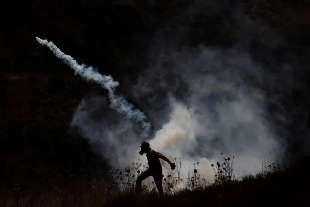 A Palestinian demonstrator returns a tear gas canister fired by Israeli troops during protest against Jewish settlements and normalizing ties with Israel, in Asira al-Qibliya in the Israeli-occupied West Bank on September 18, 2020. (Photo by Mohamad Torokman/Reuters)