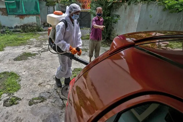 A civic staff in protective suit disinfects the parking area of an apartment where one of the residents tested positive for COVID-19 in Kolkata, India, Tuesday, September 22, 2020. The nation of 1.3 billion people is expected to become the coronavirus pandemic's worst-hit country within weeks, surpassing the United States. (Photo by Bikas Das/AP Photo)