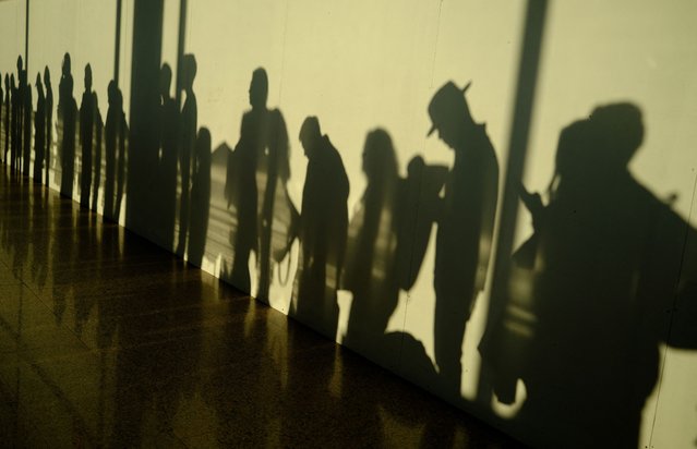 Passengers are silhouetted on a wall as they wait to board a plane at Peinador airport in Vigo, Spain on March 16, 2025. (Photo by Nacho Doce/Reuters)