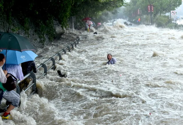 A tourist struggles in the water, before standing up and wading away, after a wave strengthened by the influence of Typhoon Dujuan hit a river bank in Hangzhou, September 2015. (Photo by Reuters/China Daily)