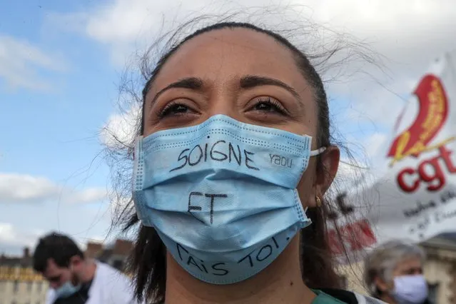 A medical worker wears as mask that reads “heal and shut up”, as she demonstrates to demand better salaries and working conditions in Paris, Thursday, October 15, 2020. French President Emmanuel Macron has announced that millions of French citizens in several regions around the country, including in Paris, will have to respect a 9pm curfew from this Saturday until Dec. 1. It's a new measure aimed at curbing the resurgent coronavirus amid second wave. The measures will require citizens in certain regions where the coronavirus is circulating to be at home after 9pm. (Photo by Michel Euler/AP Photo)