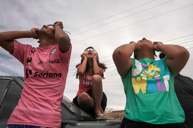 A family watches the eclipse using special glasses on April 8, 2024 in 22 de Febrero, Mexico. Millions of people have flocked to areas across North America that are in the path of totality in order to experience a total solar eclipse. During the event, the moon will pass in between the sun and the Earth, appearing to block the sun. (Photo by Cristopher Rogel Blanquet/Getty Images)