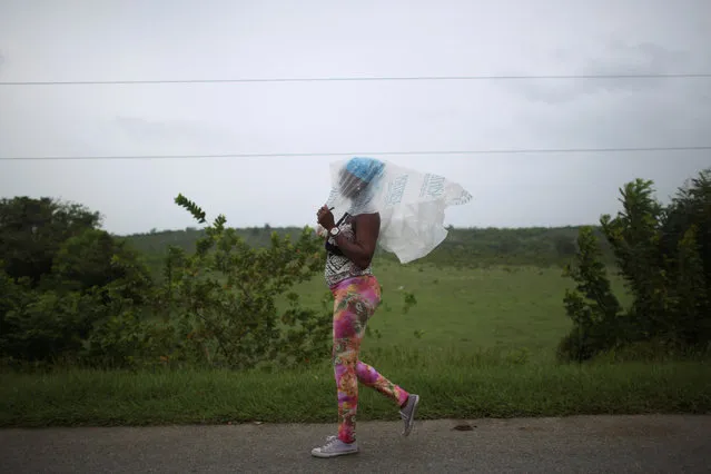 Naomi Rivera, 41, shields herself from the rain ahead of the arrival of Hurricane Matthew in Guantanamo, Cuba, October 4, 2016. (Photo by Alexandre Meneghini/Reuters)