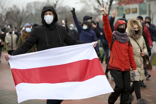 A man wearing a face mask to help curb the spread of the coronavirus holds an old Belarusian national flag during an opposition rally to protest the official presidential election results in Minsk, Belarus, Sunday, November 22, 2020. (Photo by AP Photo/Stringer)