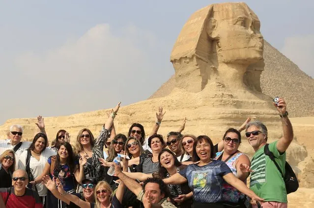 Tourists smile and cheer as they take a souvenir photo in front of the Sphinx at the Giza Pyramids on the outskirts of Cairo, Egypt, November 8, 2015. (Photo by Amr Abdallah Dalsh/Reuters)
