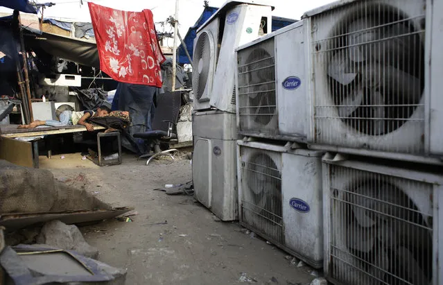 In this Tuesday, May 17, 2016 file photo, an Indian boy of a migrant daily wageworker sleeps in scorching summer temperatures near an air conditioner shop at a marketplace in New Delhi, India. Nations reached a deal Saturday, Oct. 15, 2016 to limit the use of hydrofluorocarbons, or HFCs – greenhouse gases far more powerful than carbon dioxide that are used in air conditioners and refrigerators, in a major effort to fight climate change. (Photo by Altaf Qadri/AP Photo)